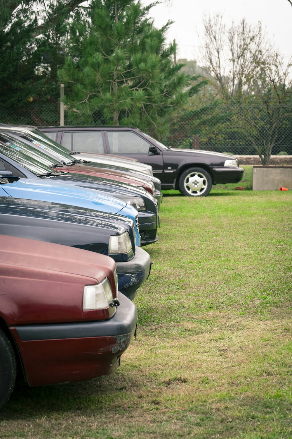 a row of parked cars sitting on top of a lush green field