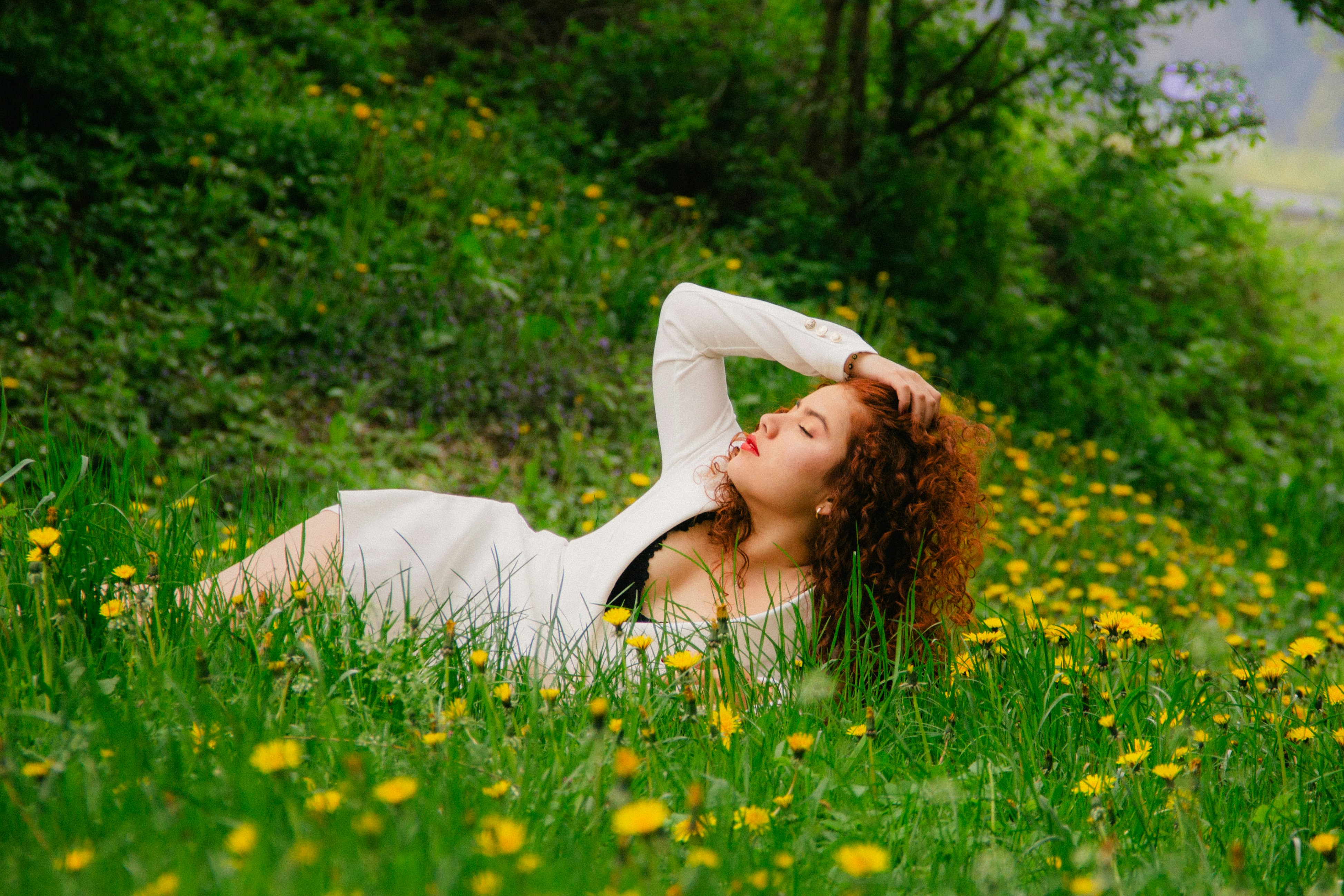a woman laying in the grass with her eyes closed