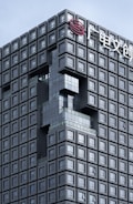 A modern architectural building with a grid-like design composed of numerous square windows. There is an artistic indentation in the facade forming an abstract shape, and a logo with Chinese characters is seen at the top.
