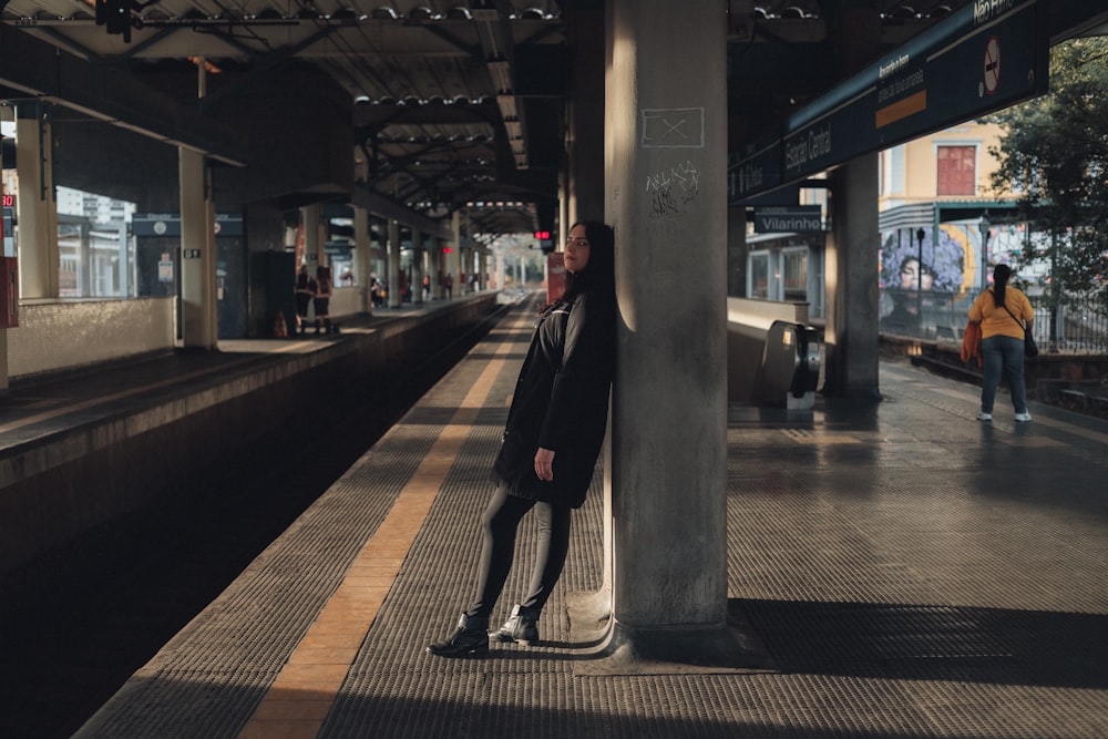 a man leaning against a pole in a train station