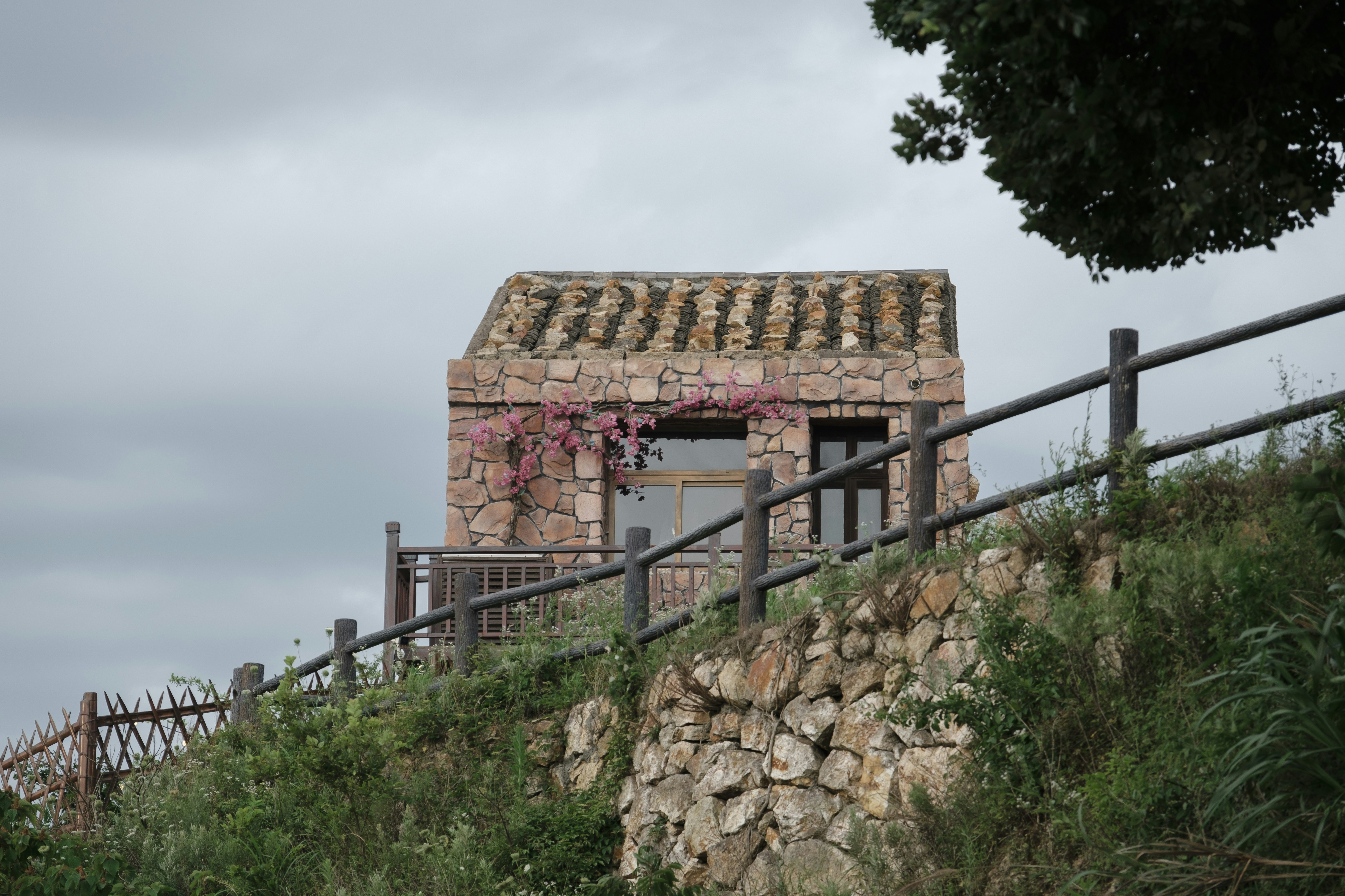 a stone building on a hill with a fence around it