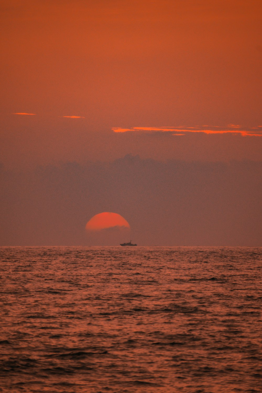 a sunset over the ocean with a boat in the distance