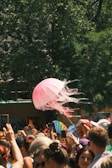 A lively crowd gathered around a colorful road show booth on a sunny day.