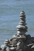 Smooth river stones stacked in a balanced tower beside gently flowing water.
