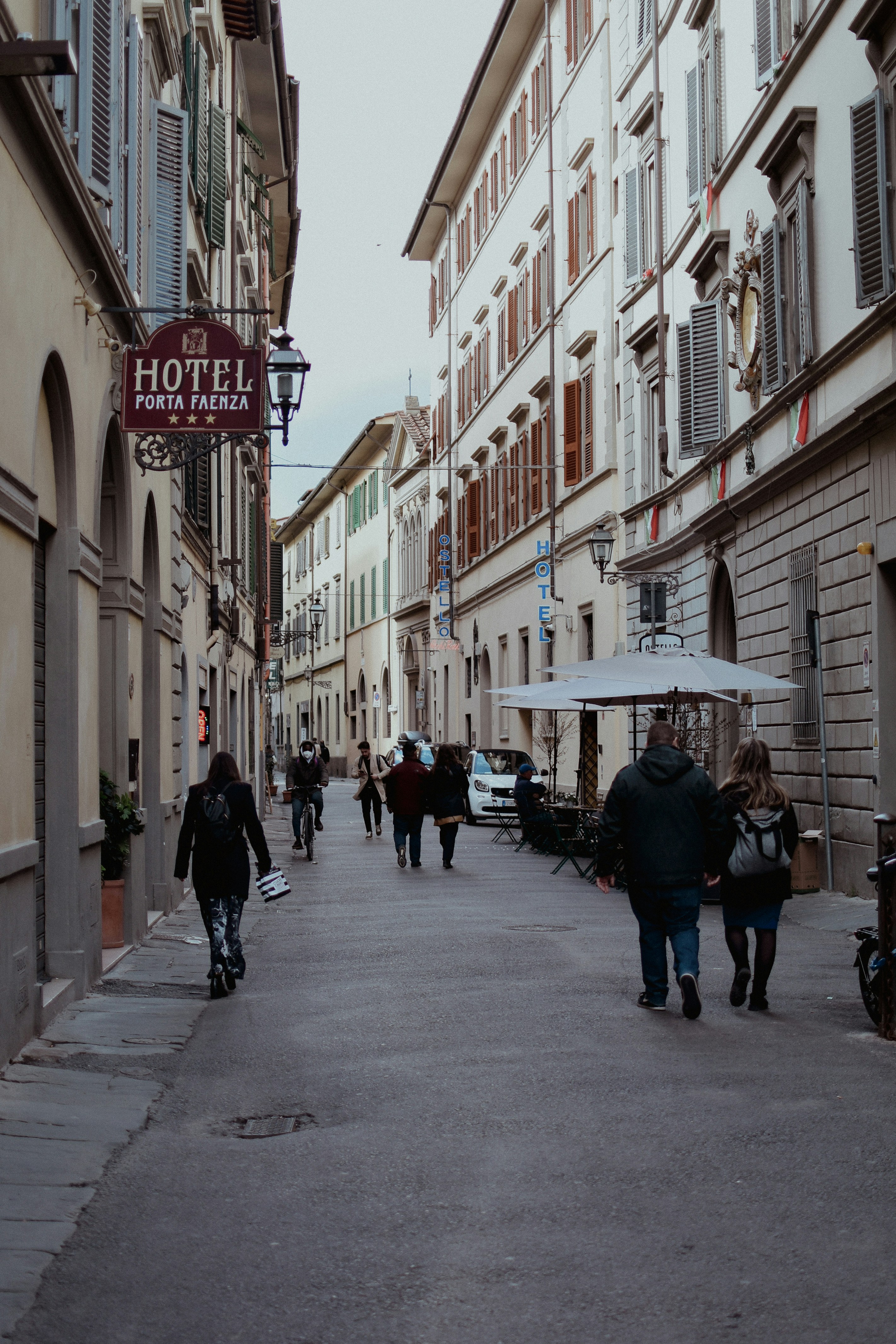 a group of people walking down a street next to tall buildings