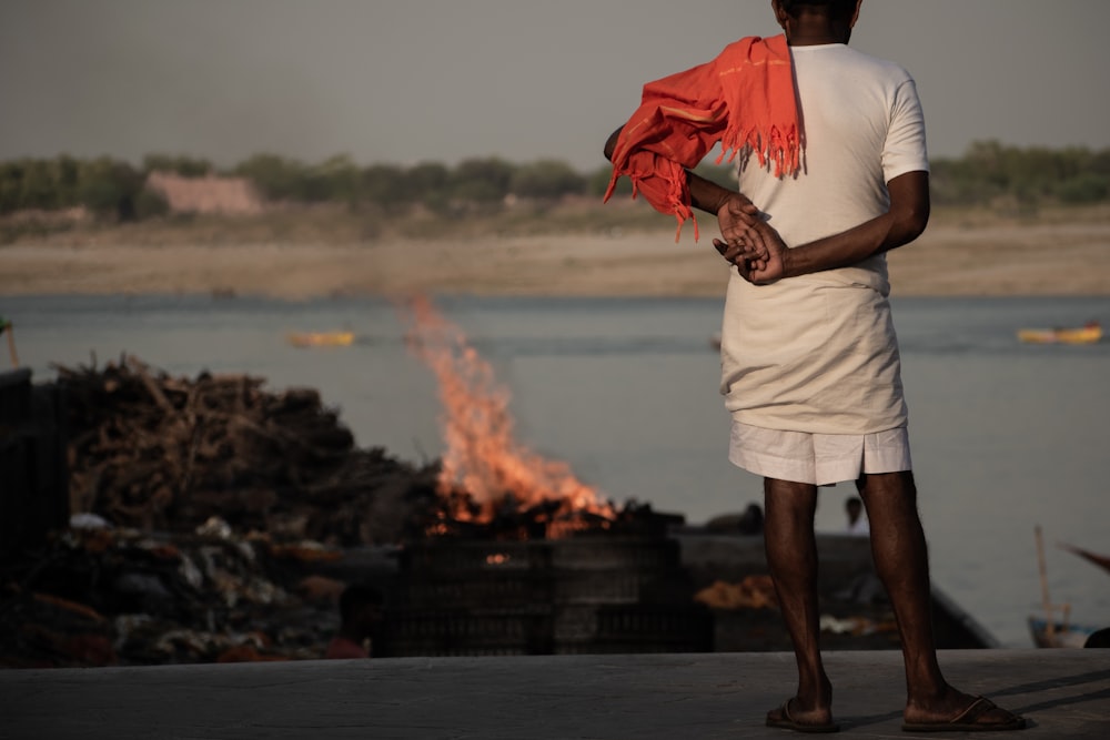 a man standing in front of a fire with a red scarf around his neck