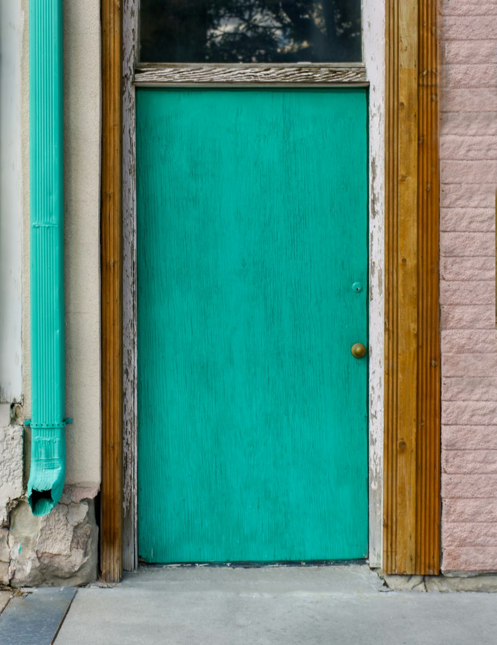 a green door with a wooden frame in front of a brick building
