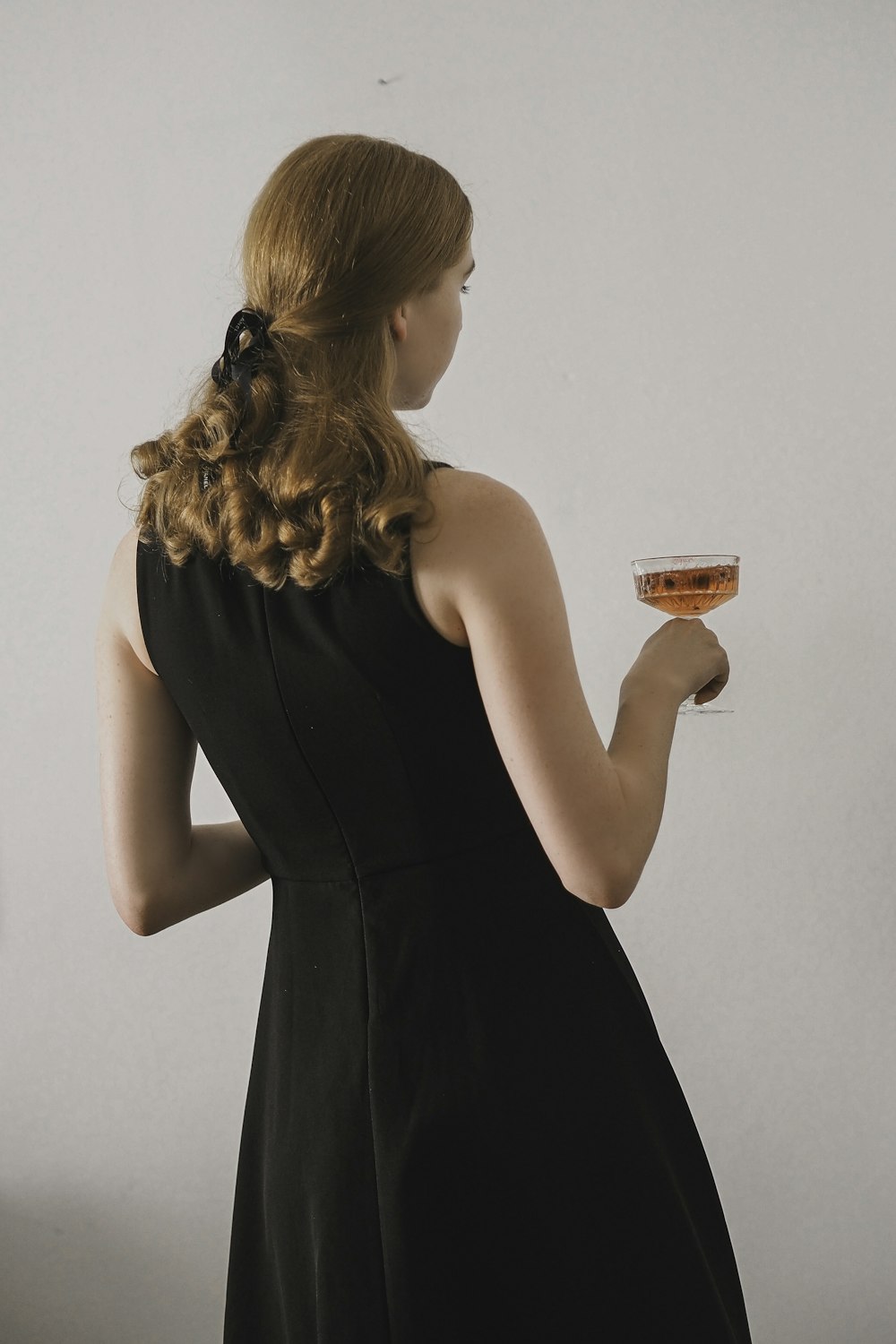 a woman in a black dress holding a glass of wine