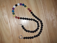 Close-up of colorful beaded necklace resting on a rustic wooden table.