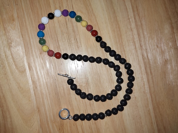 Colorful beaded necklace draped over a rustic wooden table.