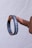 A hand holding a black lanyard or wristband between two fingers. The band has white text with the words 'external' and 'internal' printed on it. The background is a plain, light-colored backdrop.