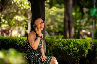 A woman in a vibrant dress smiling while enjoying a sunny day in the park.