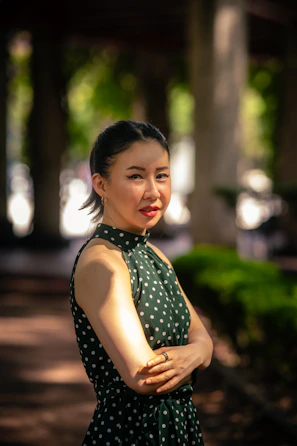 A confident plus-size woman smiling in a vibrant patterned dress outdoors.
