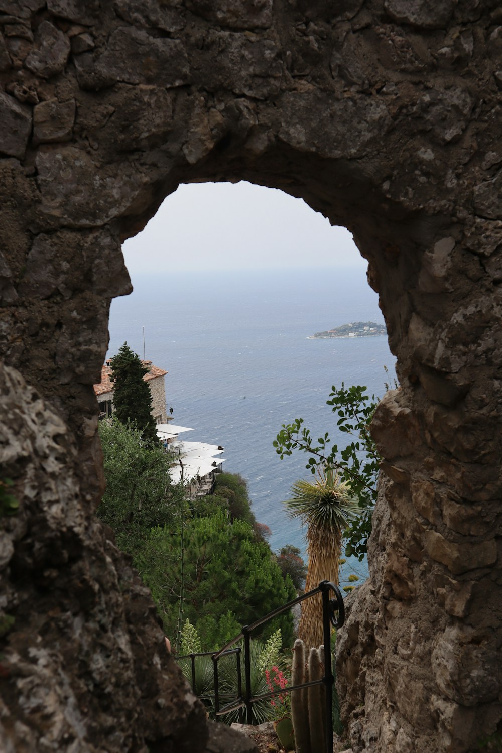 a view of a body of water through a hole in a stone wall
