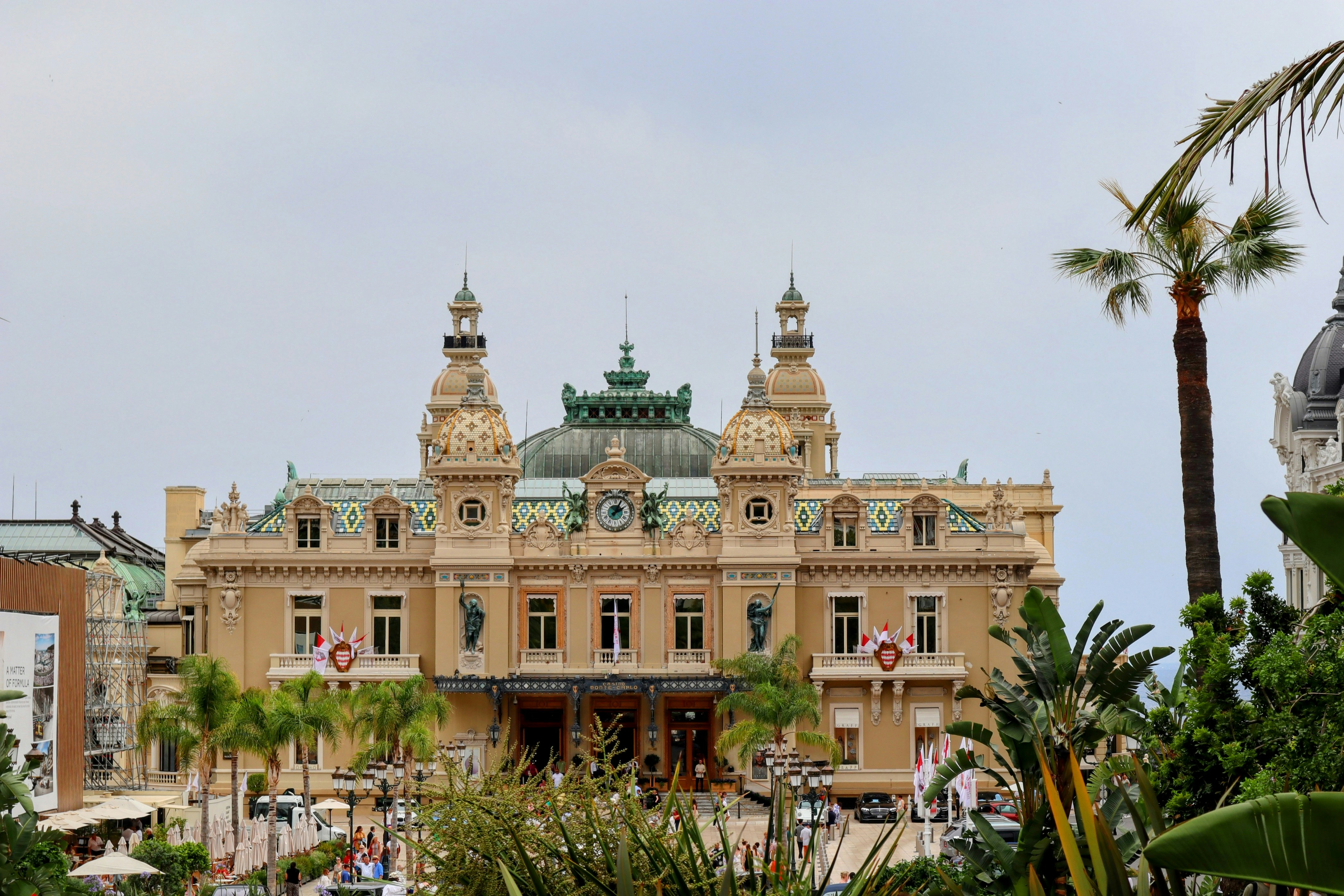 a large building with a green roof surrounded by palm trees