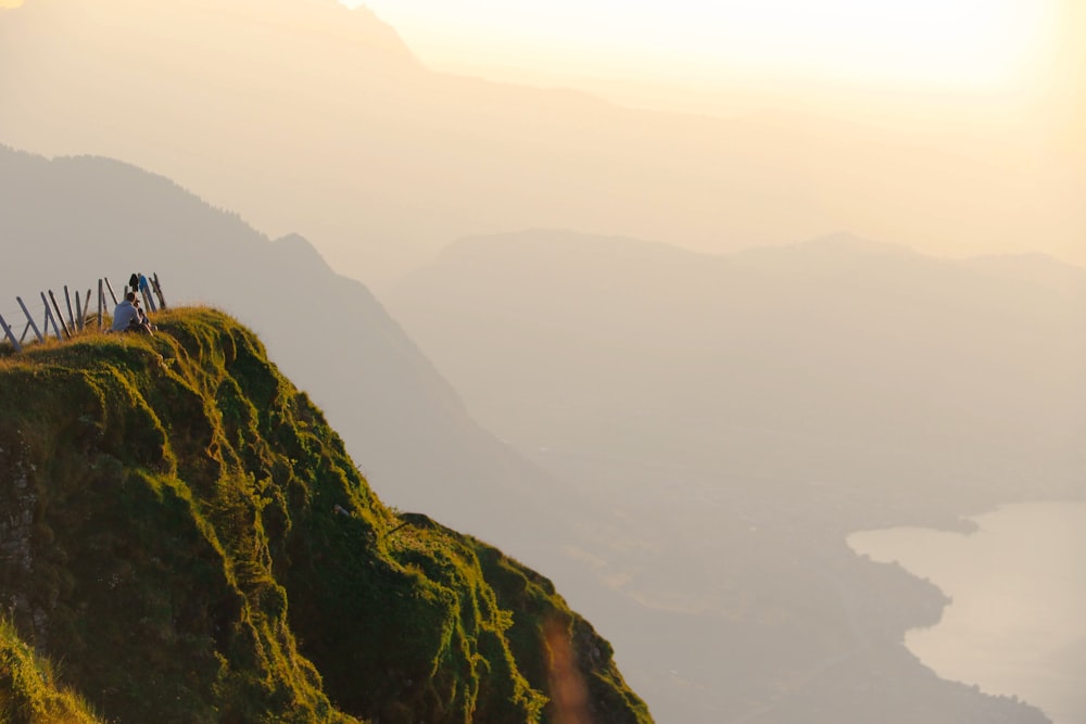 a group of people standing on top of a lush green hillside