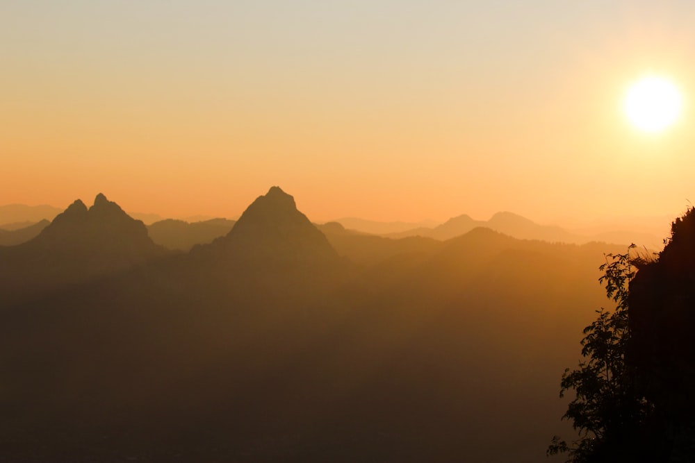 the sun is setting over a mountain range