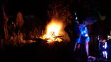 A community gathering around a campfire sharing stories, with warm terracotta tones in the background.