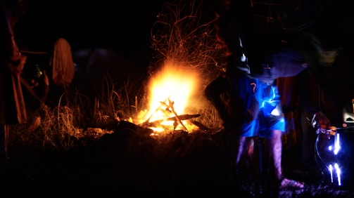 Campfire glowing warmly with silhouettes of adventurers sharing stories.