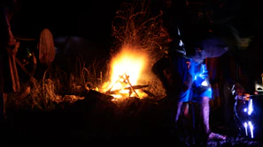 A community gathering around a campfire sharing stories, with warm terracotta tones in the background.