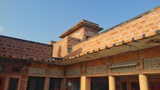 Bright daylight photo of a 5 marla house grey structure with red clay bricks and local masons working