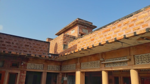 Bright daylight photo of a 5 marla house grey structure with red clay bricks and local masons working