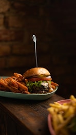 Close-up of a gourmet burger and fries served on a rustic wooden table.