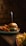 A gourmet burger with layers of beef, lettuce, tomato, and cheese is placed on a wooden table. A skewer holds the burger together. To the side, there are sweet potato fries, and another plate with regular fries is blurred in the foreground.