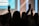 Silhouettes of people with raised arms, likely in a concert or worship setting. The background is blurred with bright vertical lights.