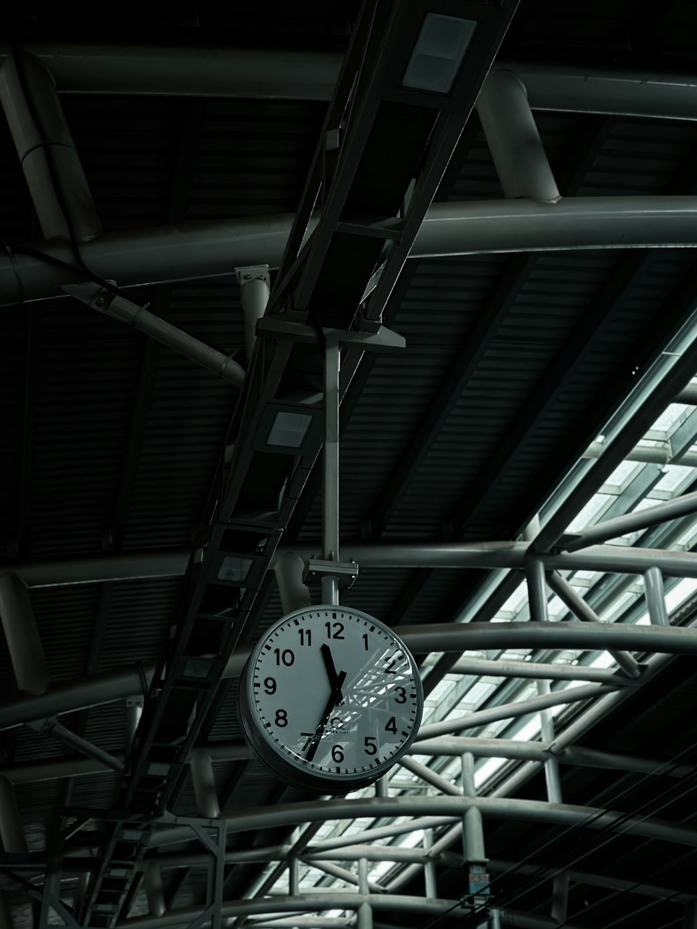 a clock hanging from the ceiling of a train station