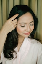 A woman gently massaging her scalp with herbal oil, smiling with healthy, shiny hair.