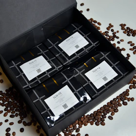 A box of assorted coffee packs arranged neatly with coffee beans scattered around.