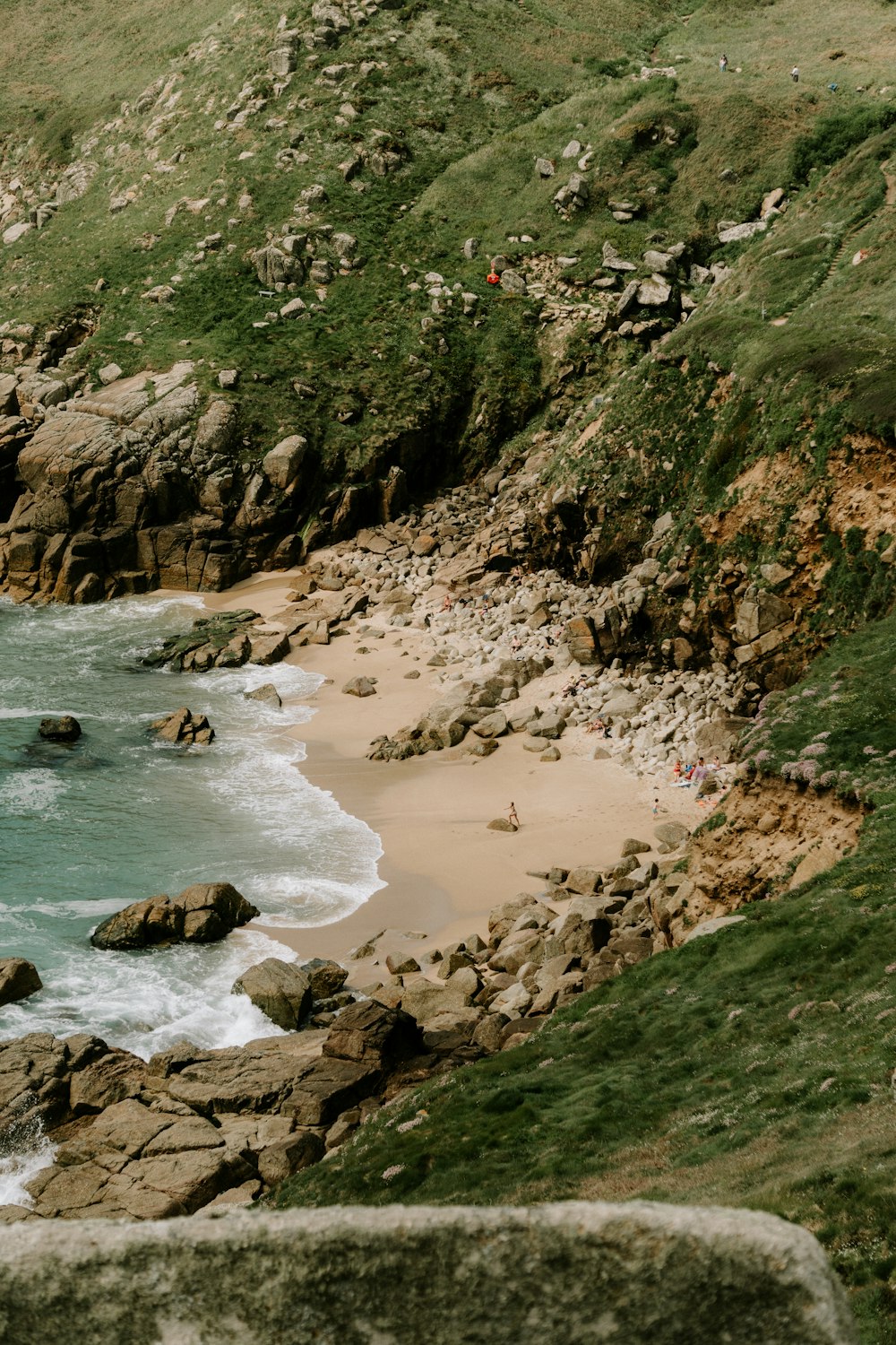 a couple of people standing on top of a rocky beach