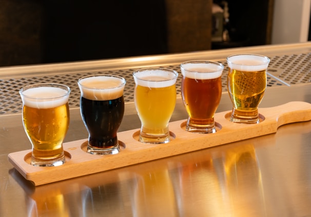 a row of beer glasses sitting on top of a wooden tray