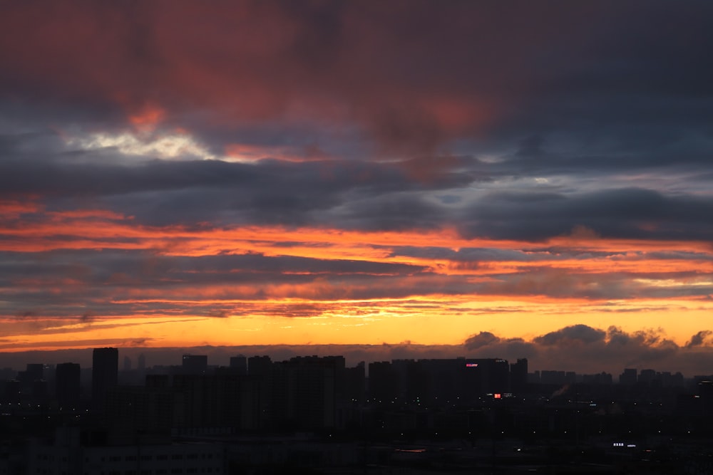 a sunset view of a city with clouds in the sky