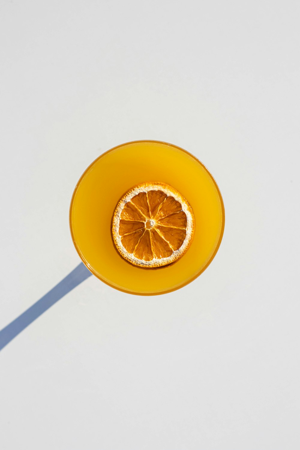an orange slice in a yellow bowl on a white surface