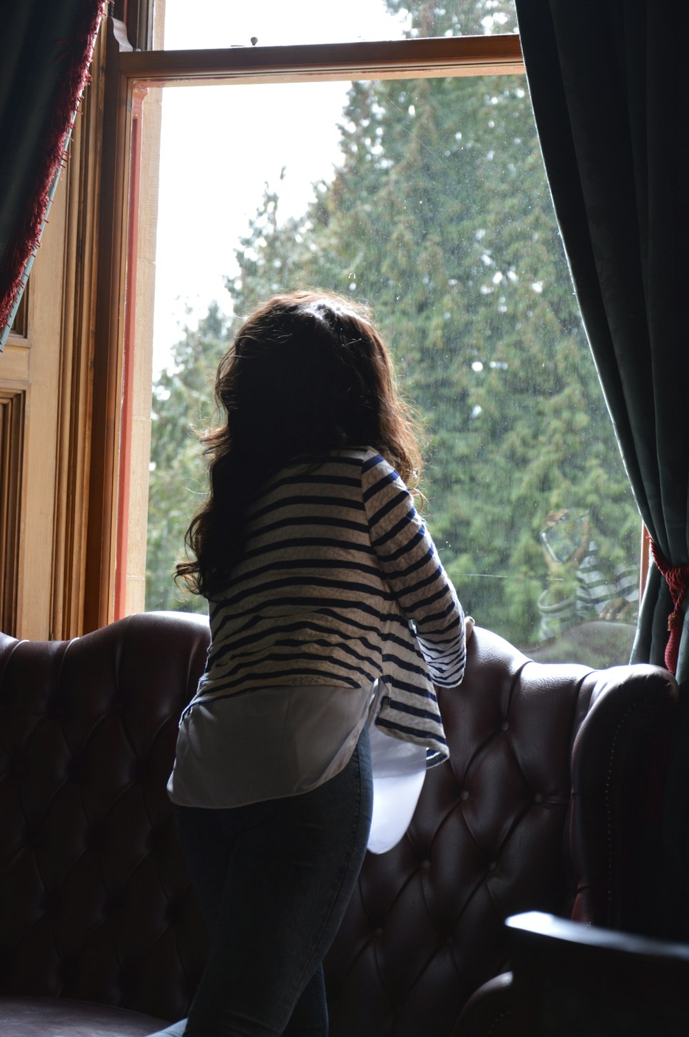 a woman leaning on a couch looking out a window