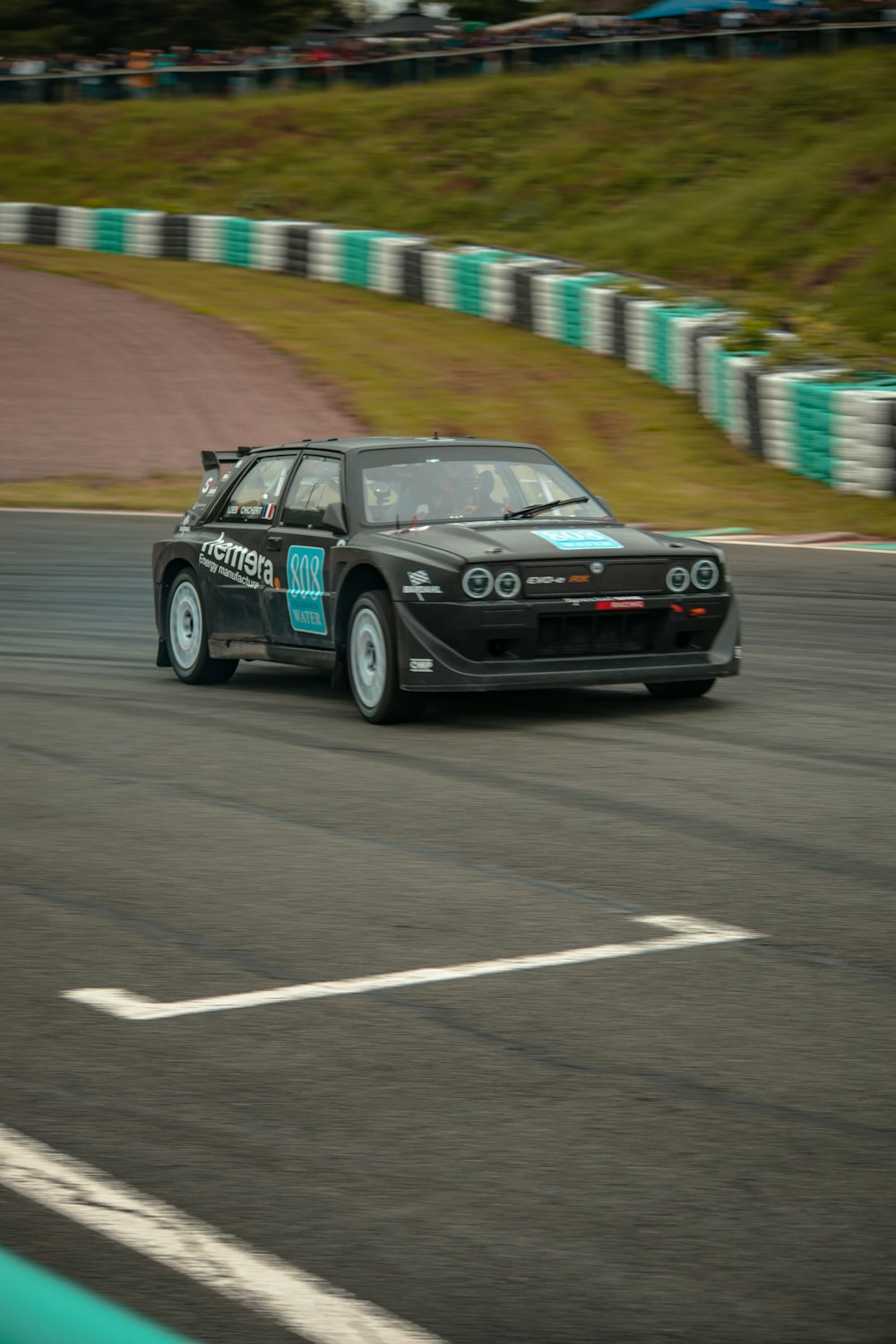 a black car driving down a race track