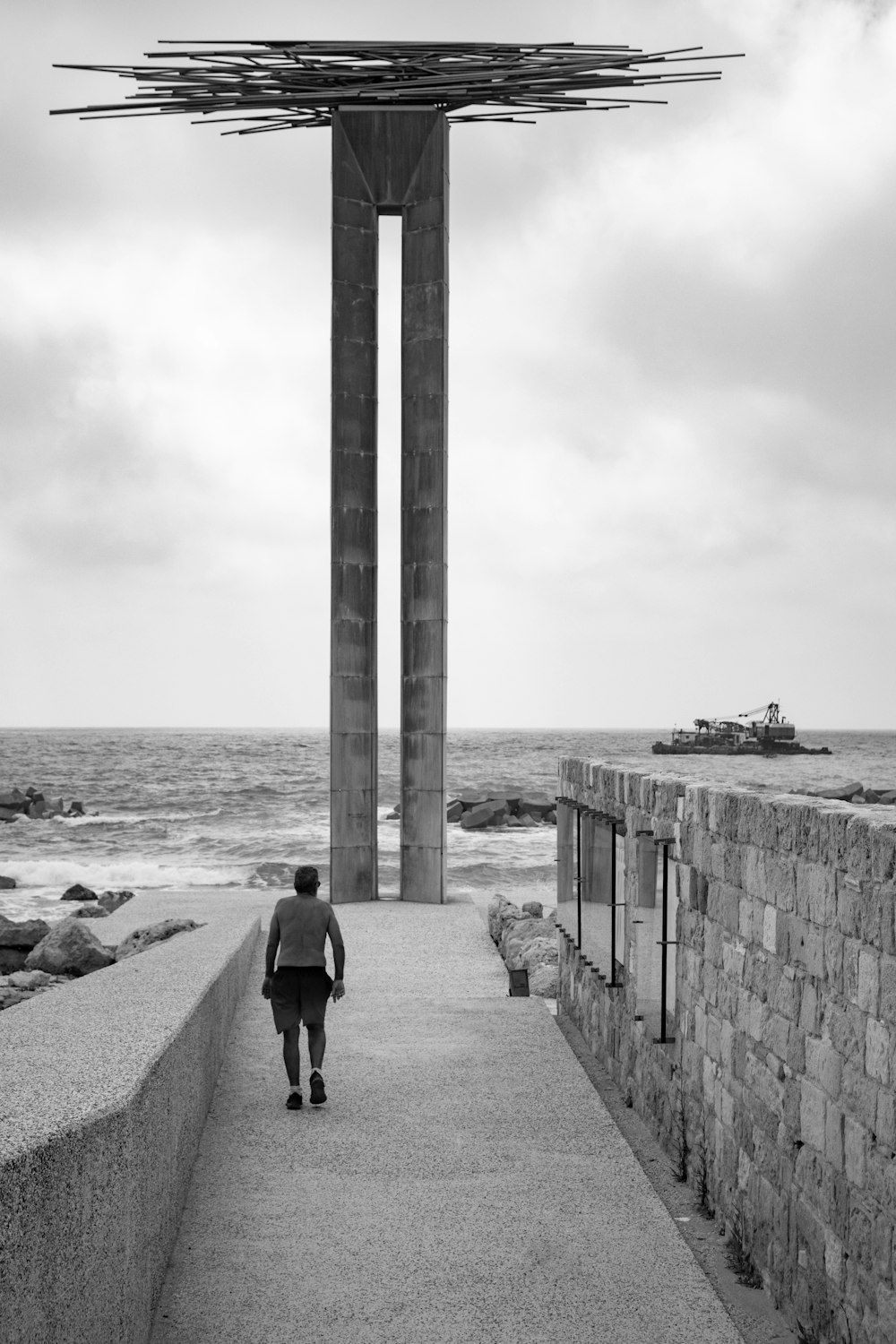 a man walking down a walkway next to the ocean