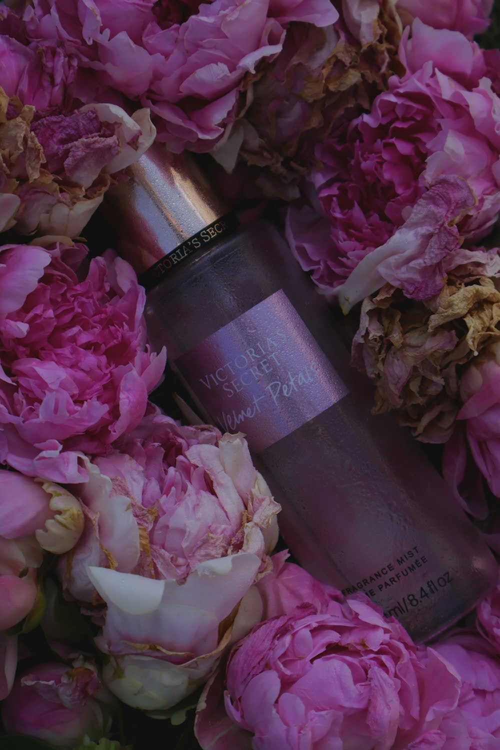 ピンクの花に囲まれた香水のボトルのクローズアップ