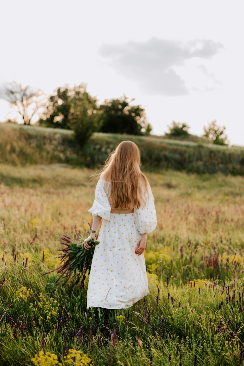 a girl in a white dress walking through a field