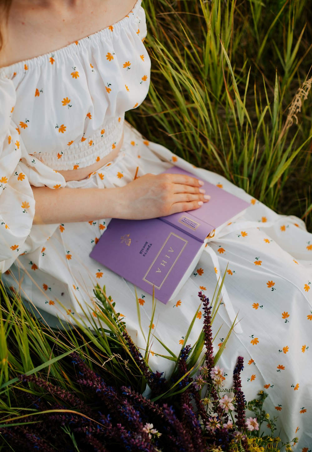 a woman is sitting in the grass with a book