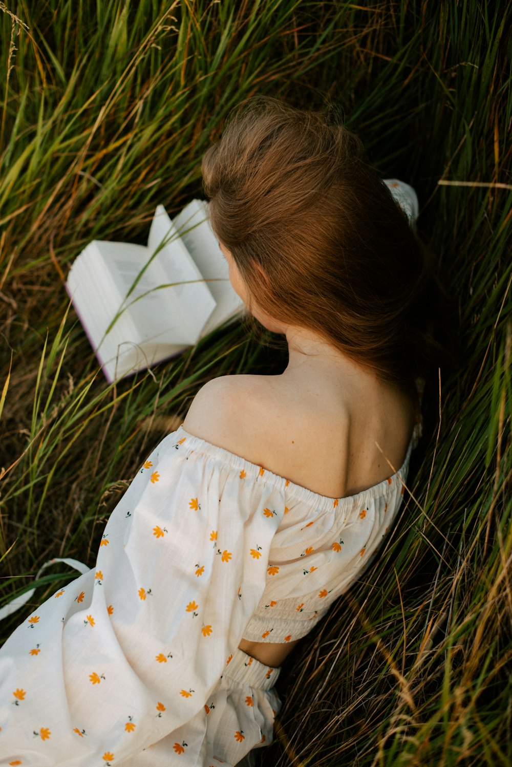 a woman laying in the grass with a book