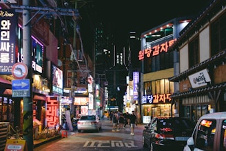 Night view of a vibrant Gangnam nightlife street with bright neon signs.