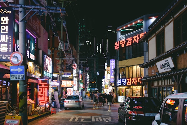 Night view of a vibrant Gangnam nightlife street with bright neon signs.