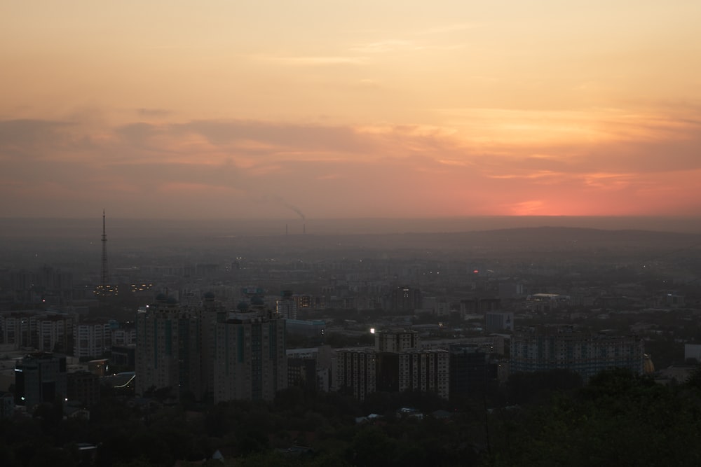 the sun is setting over a city with tall buildings