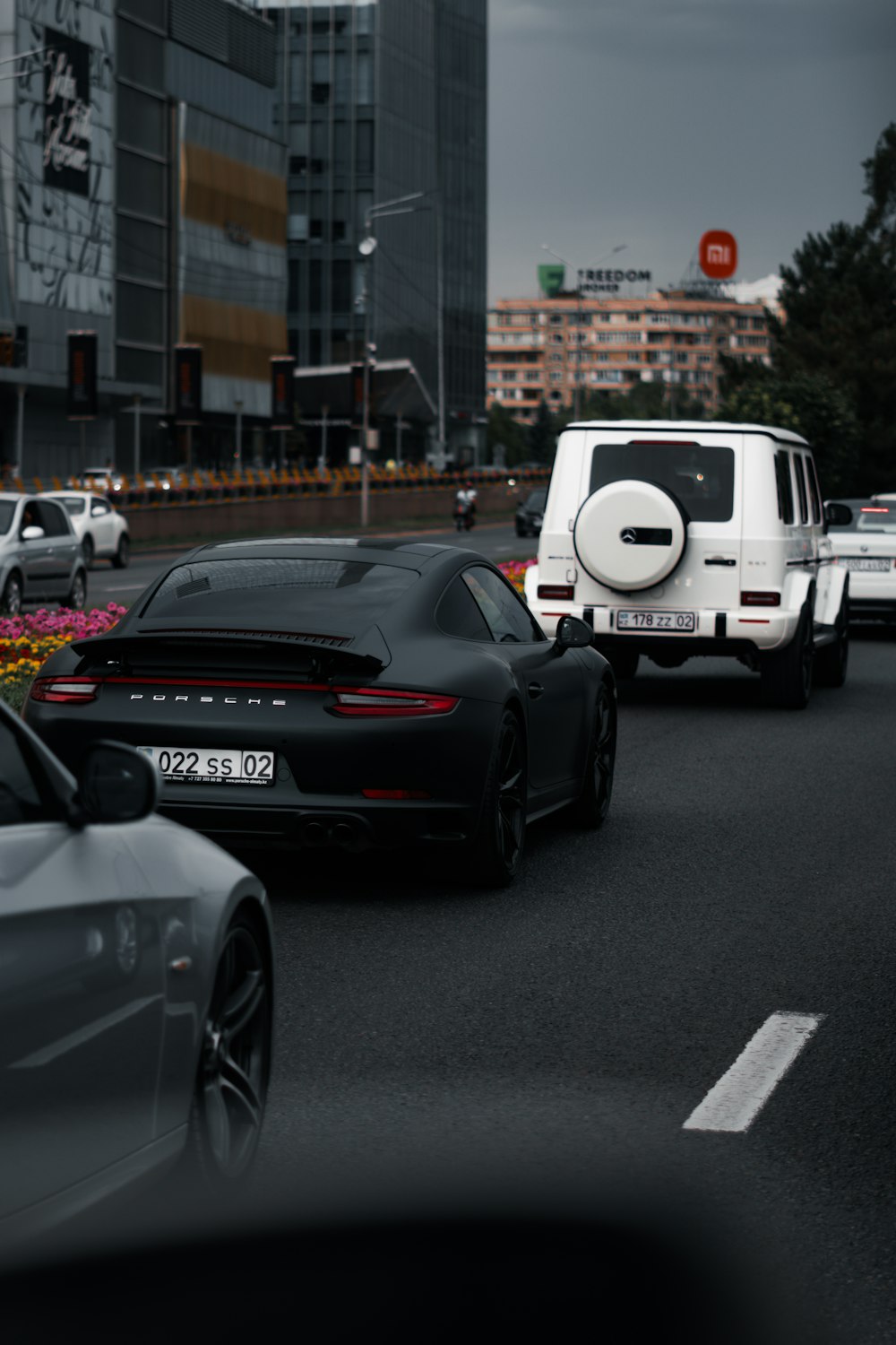 a group of cars driving down a street next to tall buildings