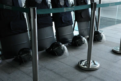 Tactical gloves and protective helmets lined up on an industrial metal surface with safety orange accents.