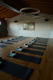 a room filled with lots of yoga mats on top of a wooden floor