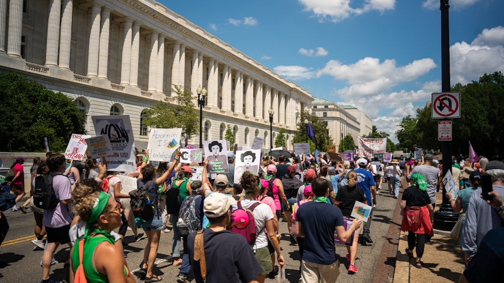 a group of people walking down a street holding signs